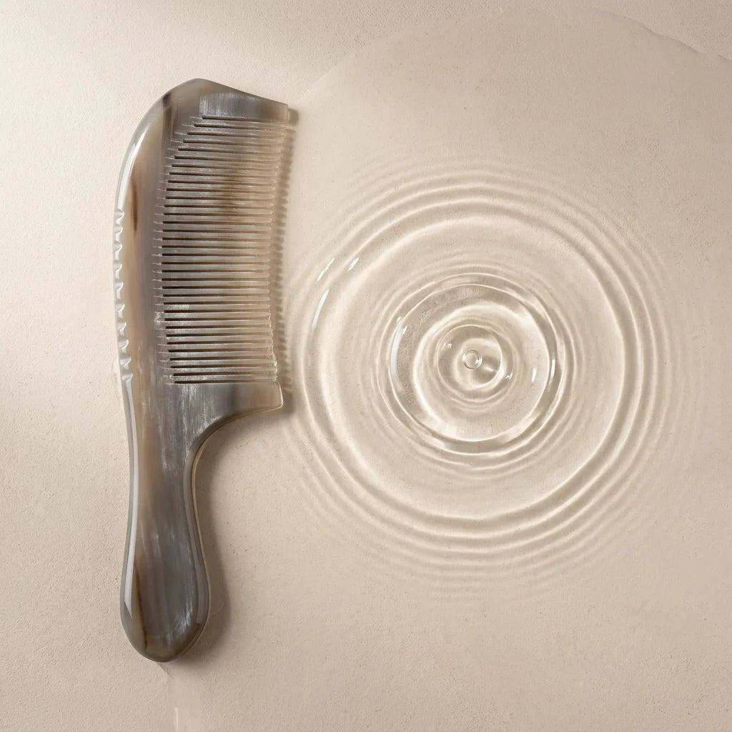 A Cozuy anti static comb resting by clear water ripples, perfect for a mindful scalp care routine to gently detangle.