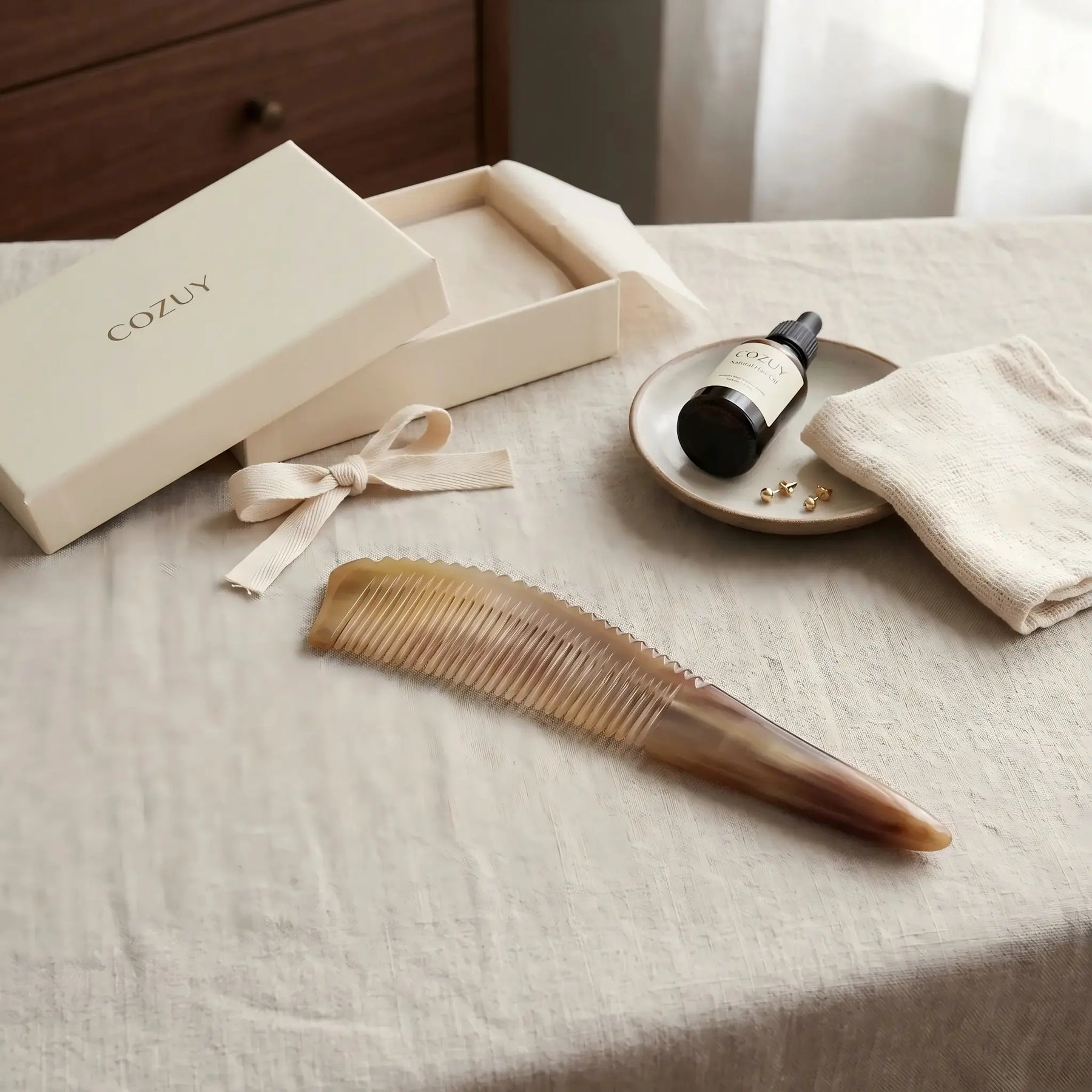 COZUY amber ox horn pointed-tail comb in a styled still life showing amber color variation and polished finish. detail image 6