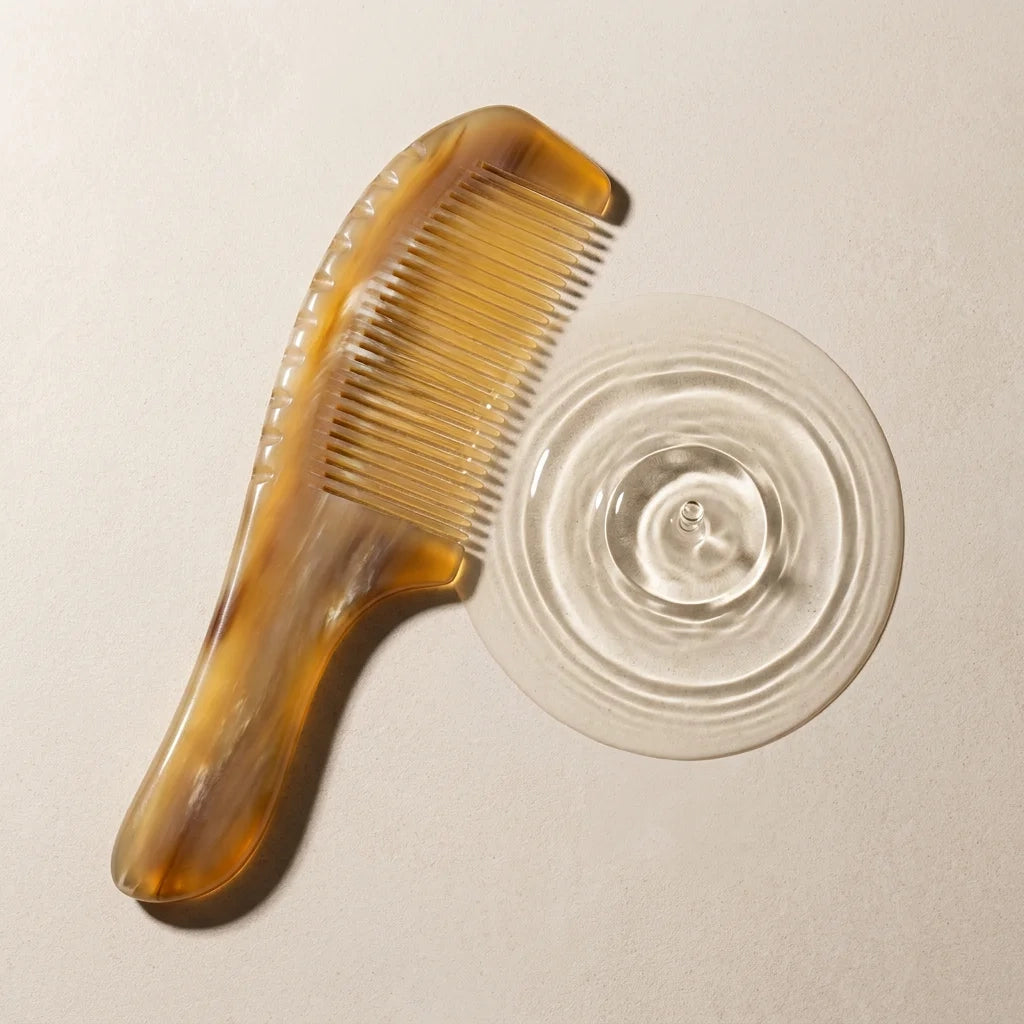 A Cozuy anti static comb resting by clear water ripples, perfect for a mindful scalp care routine.