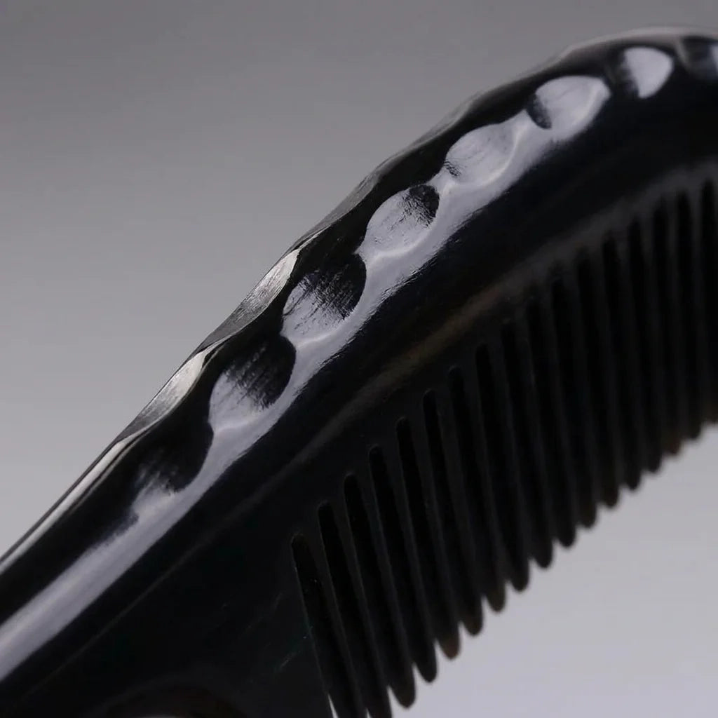 Extreme close-up of a black horn comb's sculpted scalloped spine, expertly crafted for deep scalp massage.