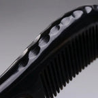 Extreme close-up of a black horn comb's sculpted scalloped spine, expertly crafted for deep scalp massage.