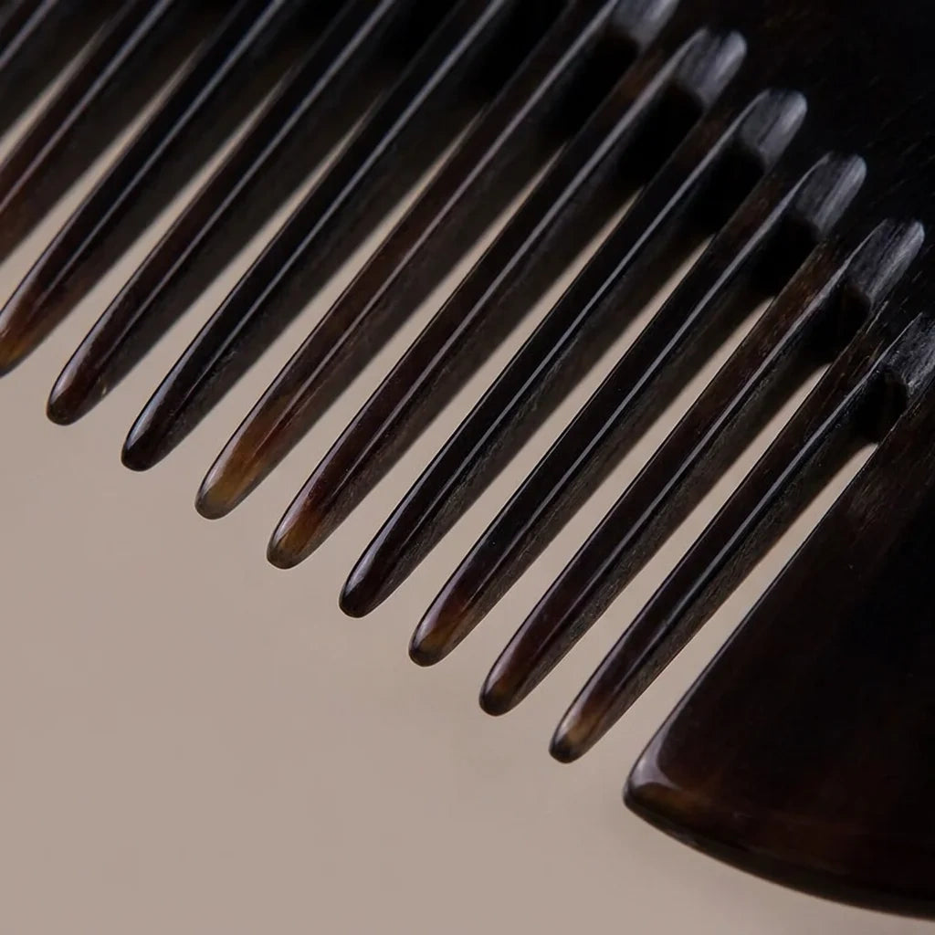 Extreme close-up of dark rounded horn comb teeth, precision crafted for targeted scalp massage therapy.