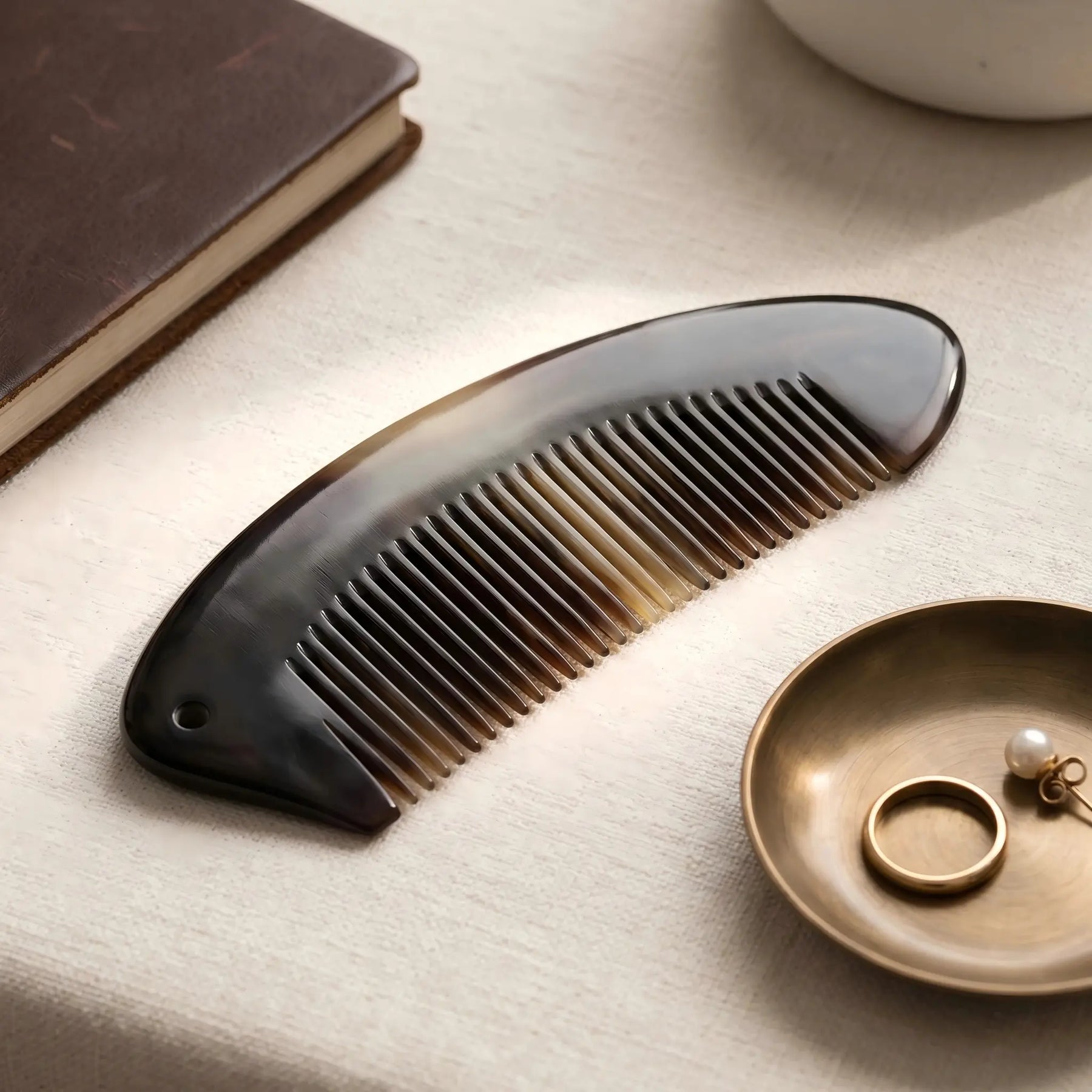 COZUY black ox horn crescent pocket comb in a styled still life showing polished black horn and curved profile. detail image 6