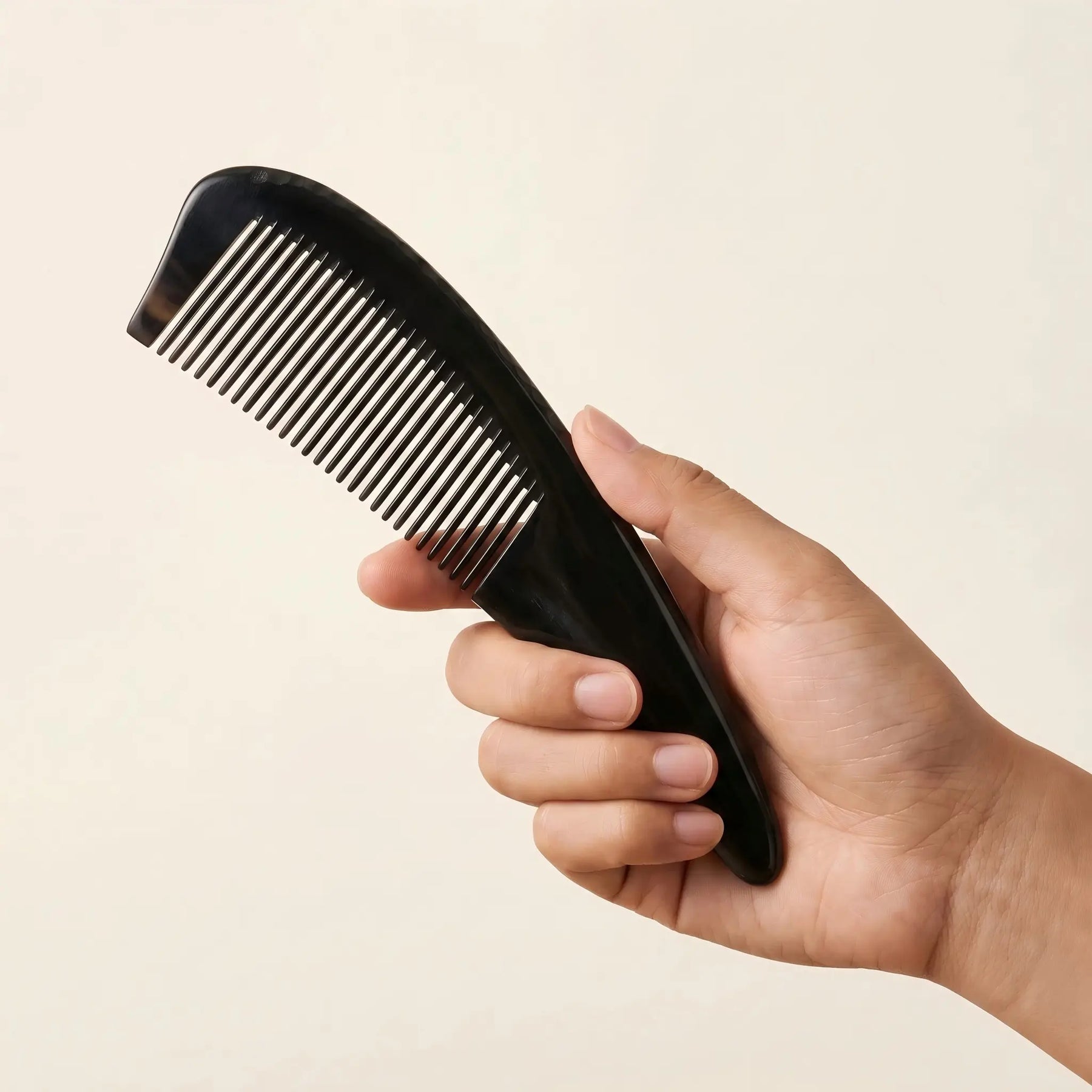 Hand holding COZUY black ox horn pointed-tail comb to show broad spine and pointed handle. detail image 3