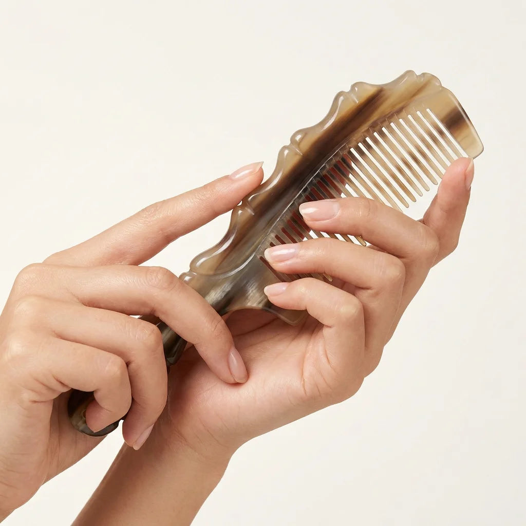 Hands holding an ergonomic yak horn comb with a scalloped edge, designed for daily tension relief.