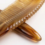 Extreme close-up of a yellow horn comb's scalloped spine and smooth teeth, crafted for scalp micro-circulation.
