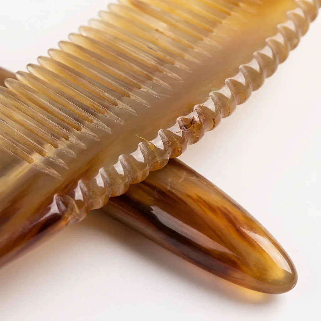 Extreme close-up of a yellow horn comb's scalloped spine and smooth teeth, crafted for scalp micro-circulation.