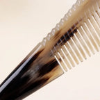 Close-up of a yellow horn comb featuring a scalloped spine and smooth teeth, crafted for scalp micro-circulation.