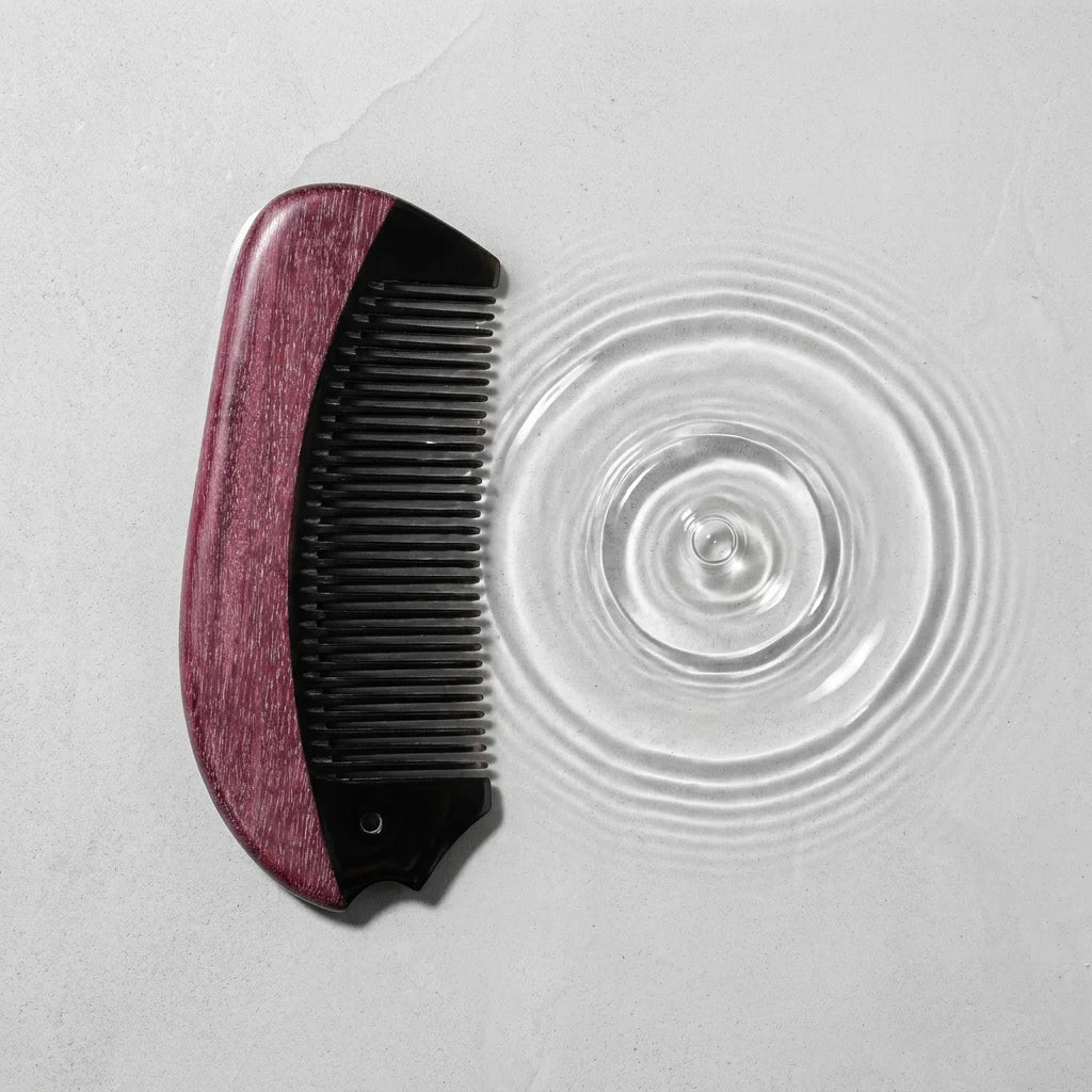 Natural horn comb beside water ripples on a light stone surface, suggesting a calm scalp ritual.