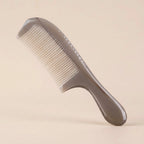 A translucent Cozuy natural horn comb standing on a beige background, designed to help reduce static and smooth flyaways.