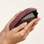 Hands softly holding a smooth natural horn comb, ergonomic design for daily tension and stress relief.