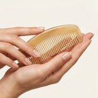 Hands gently holding a smooth, curved translucent sheep horn comb, crafted for daily tension and stress relief.