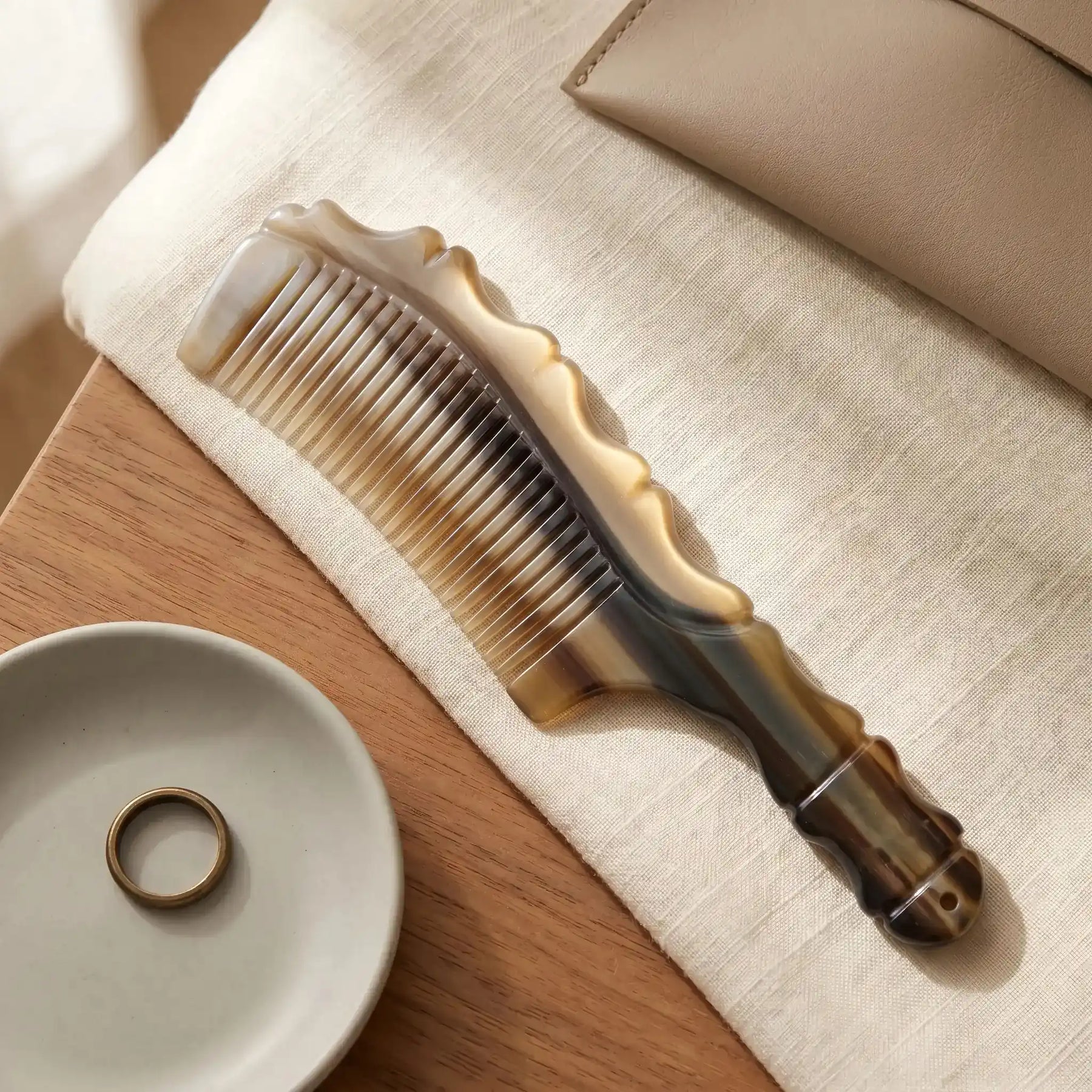 COZUY natural yak horn wave-spine comb in a styled still life showing patterned yak horn and carved wave profile. detail image 6
