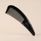 An elegant Cozuy ox horn comb standing on a minimalist beige background, designed to help reduce static and smooth hair.