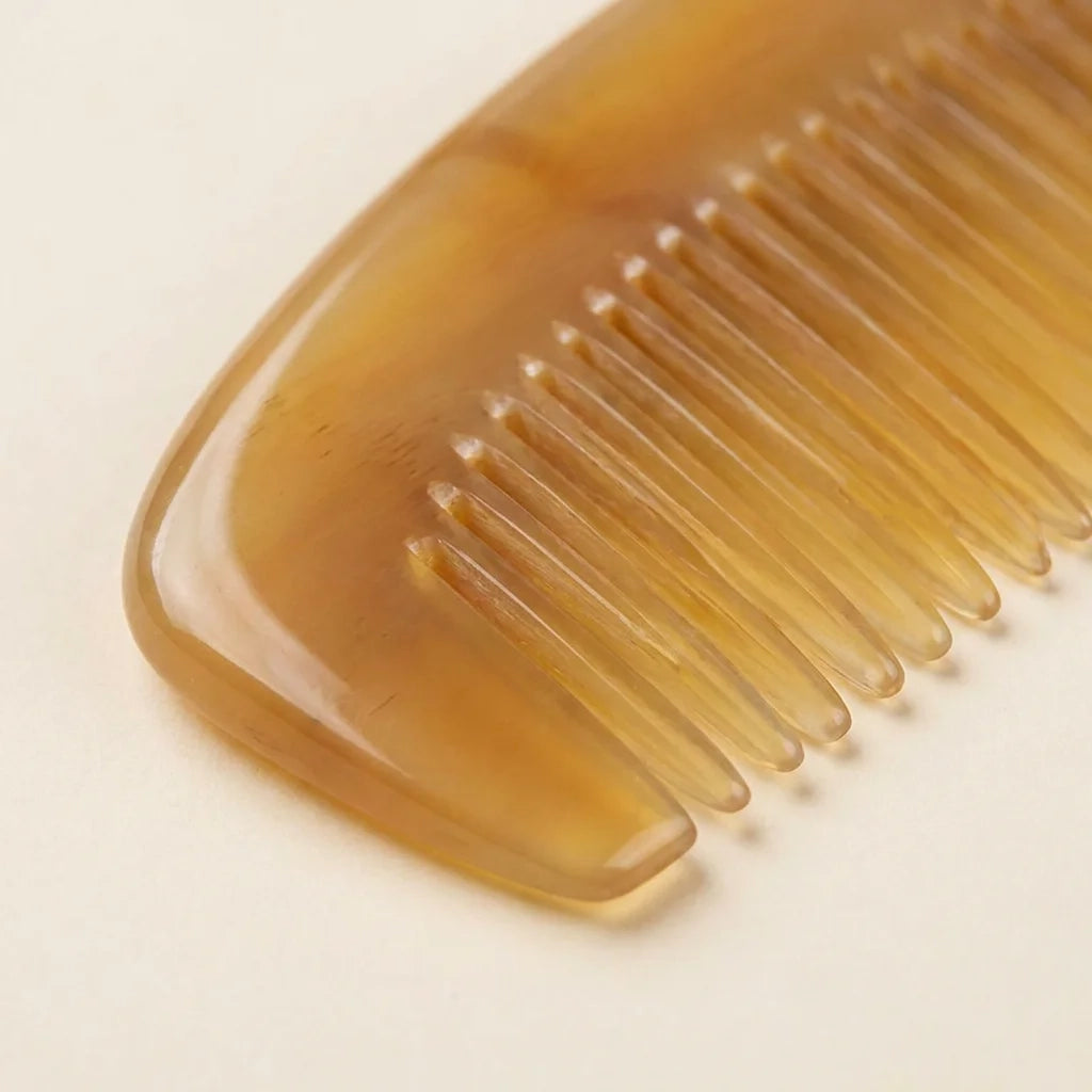 Extreme close-up of translucent sheep horn comb teeth, smoothly rounded for gentle scalp massage therapy.