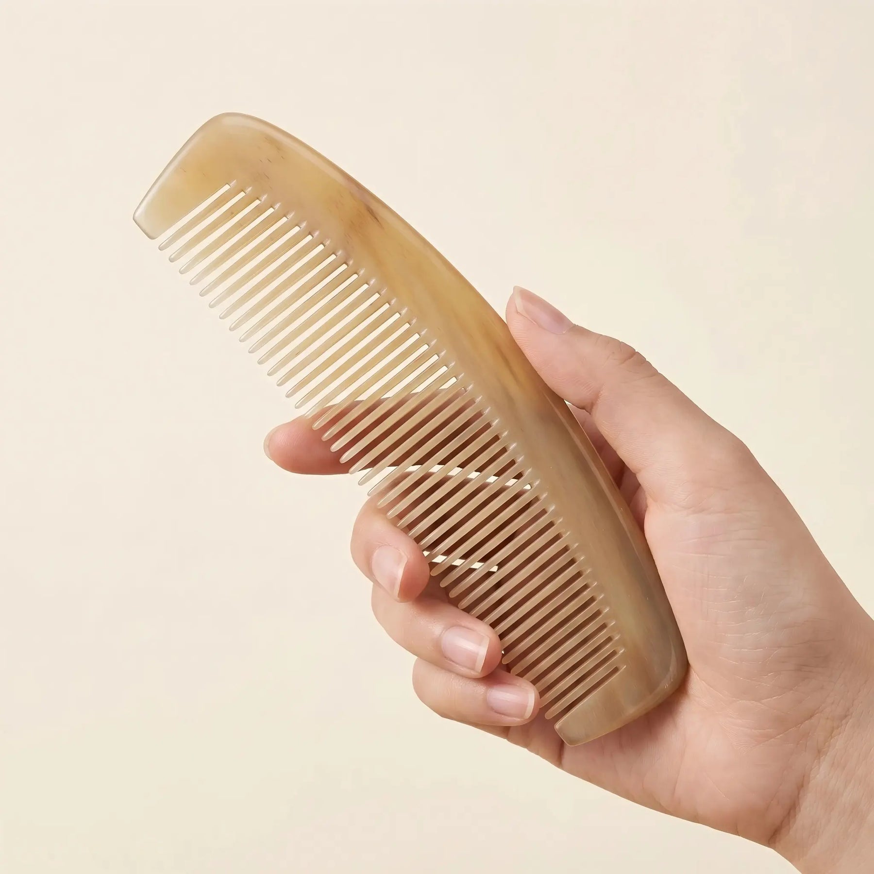 Hand holding COZUY translucent sheep horn pocket comb to show slim curved body and portable scale. detail image 3
