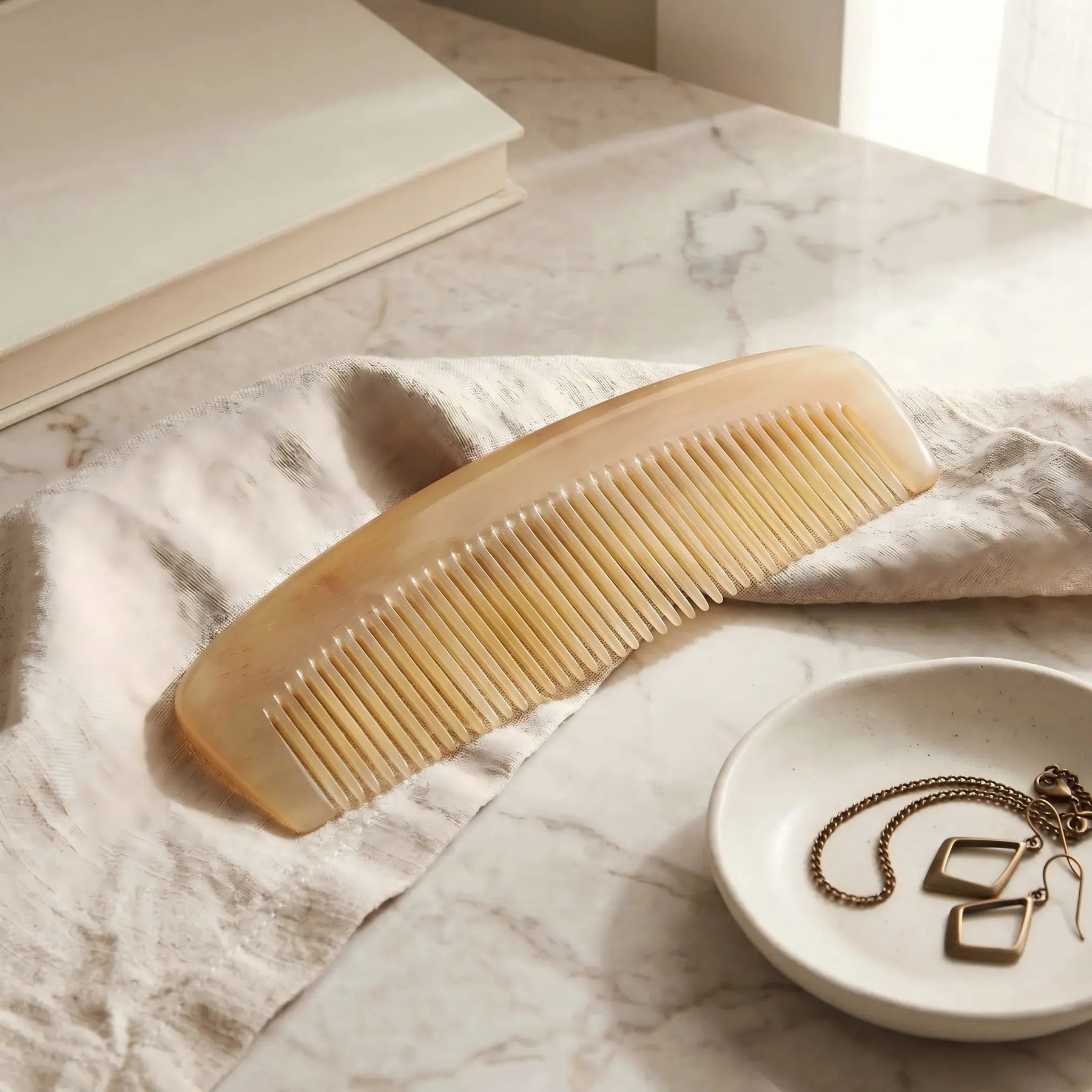 COZUY translucent sheep horn pocket comb in a styled still life showing translucent horn layers and compact profile. detail image 6