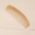 Translucent sheep horn pocket comb floating on a soft beige background, an elegant tension and stress relief tool.