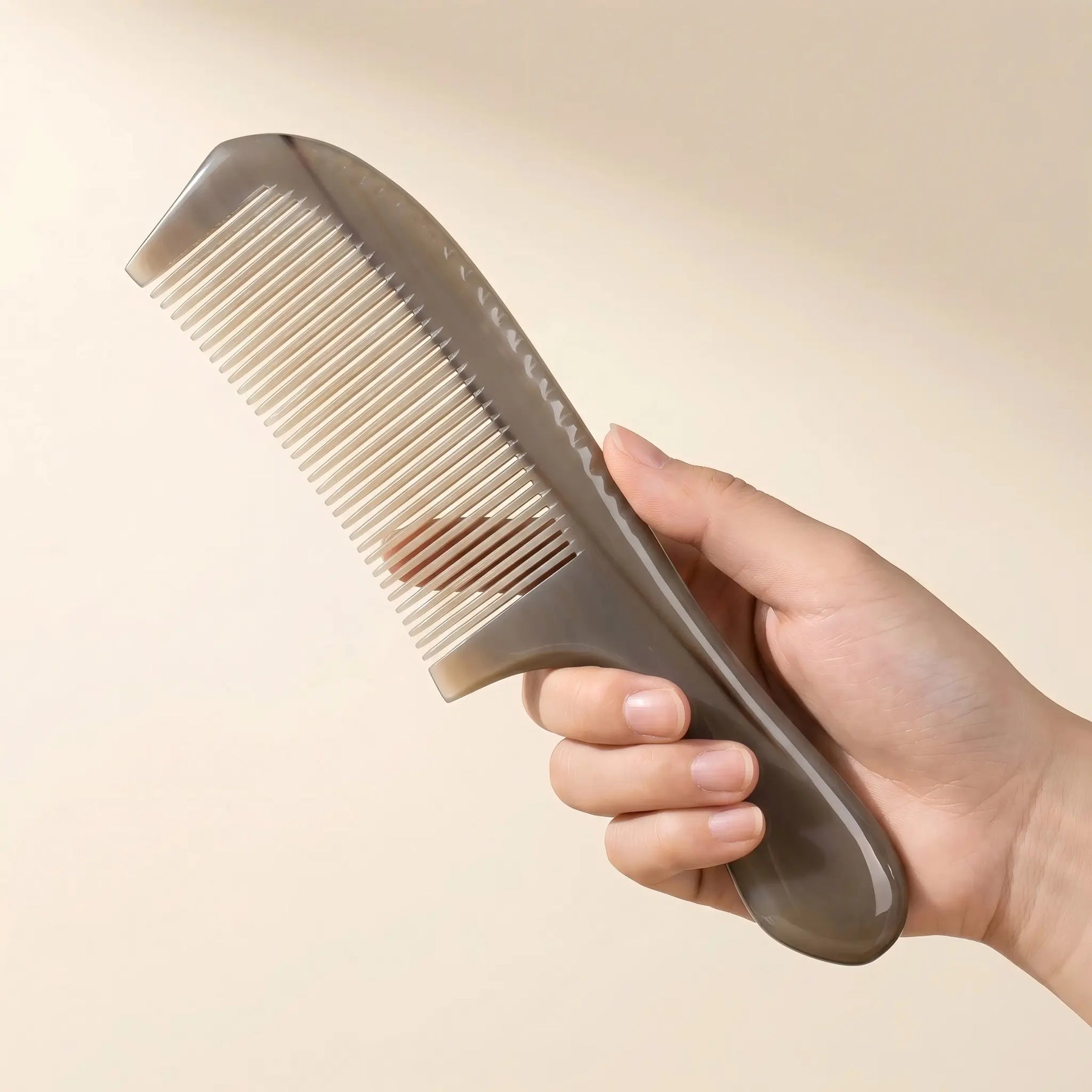 Hand holding COZUY translucent yak horn handle comb to show large rounded handle and full-length scale. detail image 3