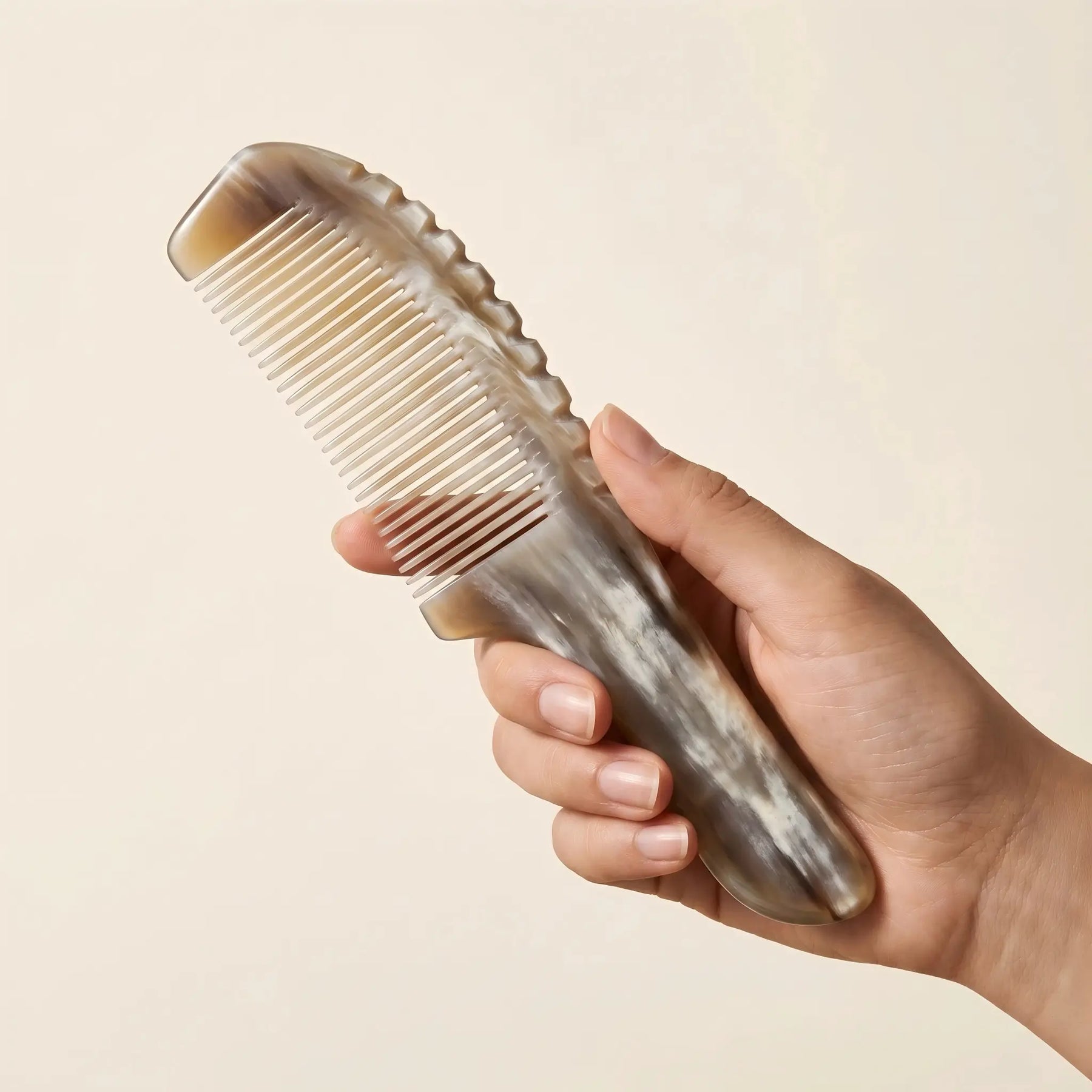 Hand holding COZUY marbled white yak horn comb to show scalloped spine and smooth rounded handle. detail image 3