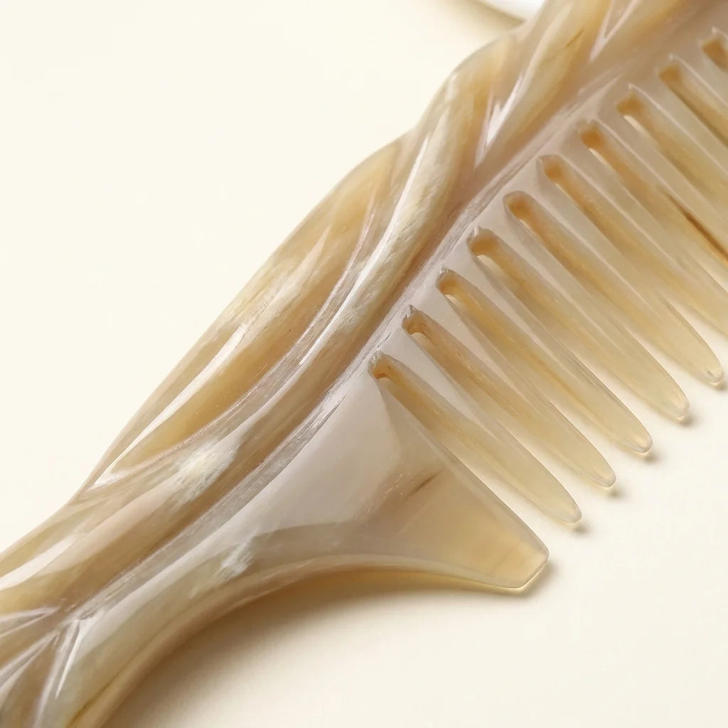 Extreme close-up of smooth carved white yak horn comb teeth, crafted for gentle scalp massage therapy.