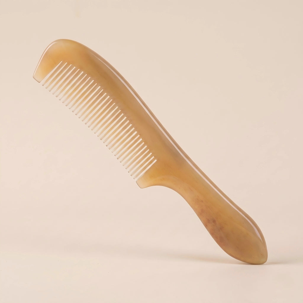 Elegant yellow natural horn comb with a handle resting on a soft beige background, a perfect artisan gift.