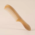Elegant yellow natural horn comb with a handle resting on a soft beige background, a perfect artisan gift.