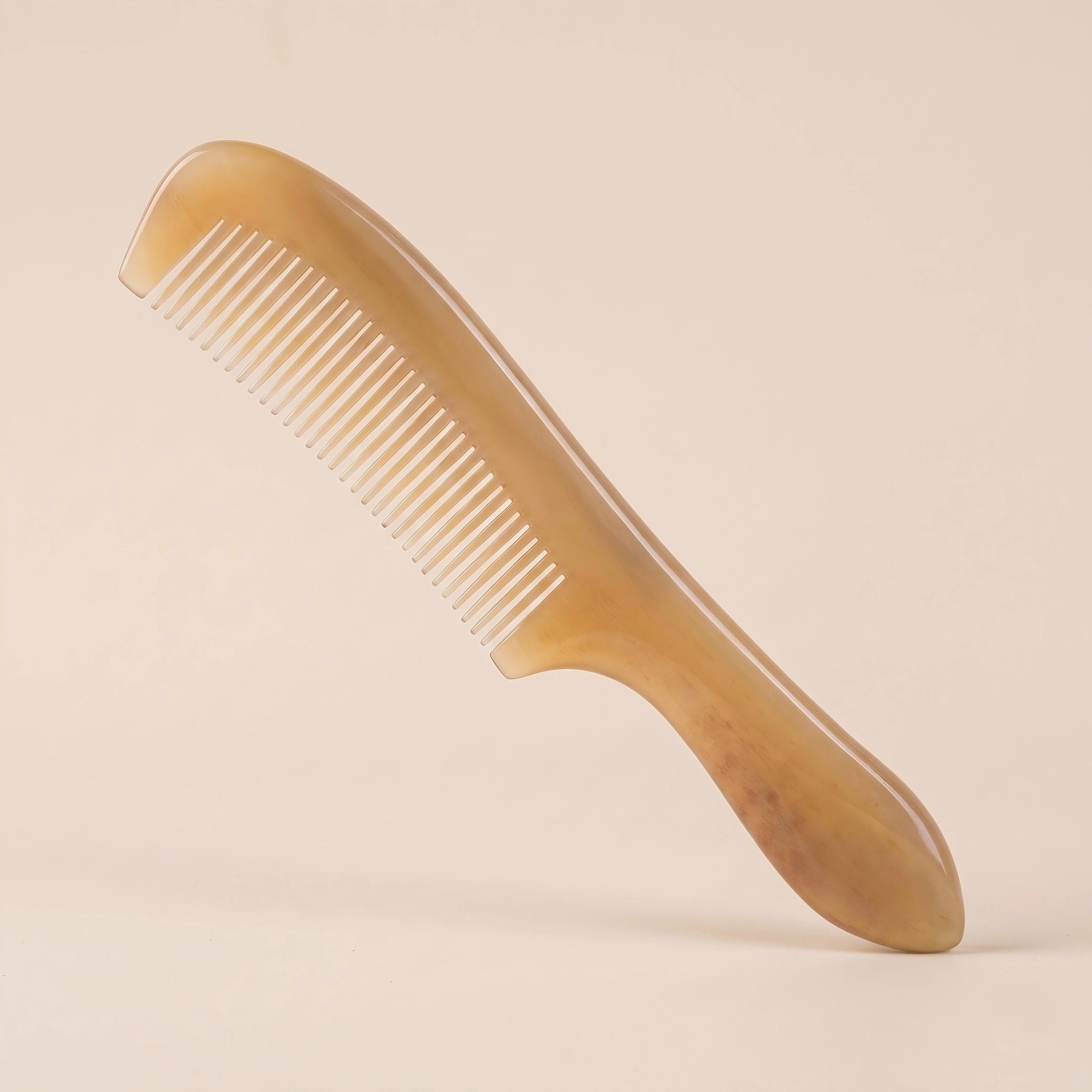 Elegant yellow natural horn comb with a handle resting on a soft beige background, a perfect artisan gift.