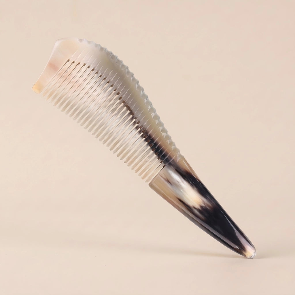 Pointed yellow horn gua sha comb with a dark tip resting on a beige background, an elegant artisan gift.