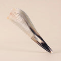 Pointed yellow horn gua sha comb with a dark tip resting on a beige background, an elegant artisan gift.