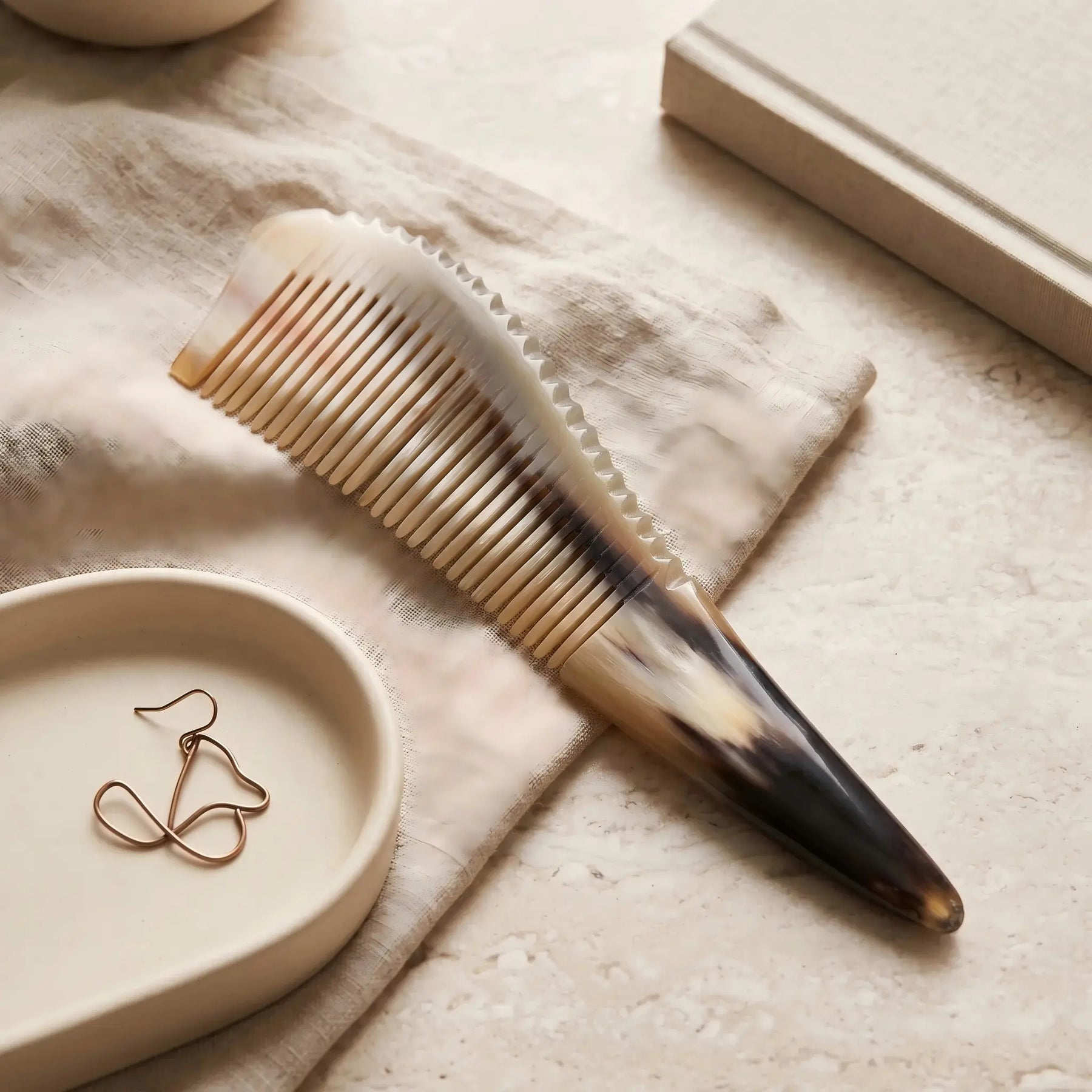 COZUY yellow ox horn pointed-tail comb in a styled still life showing golden horn variation and long silhouette. detail image 6